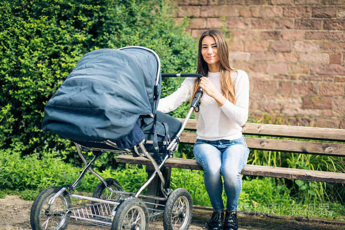 年轻母亲与婴儿推车在公园里