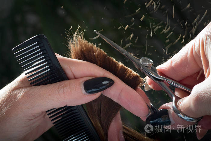 用剪刀修剪棕色头发的理发师