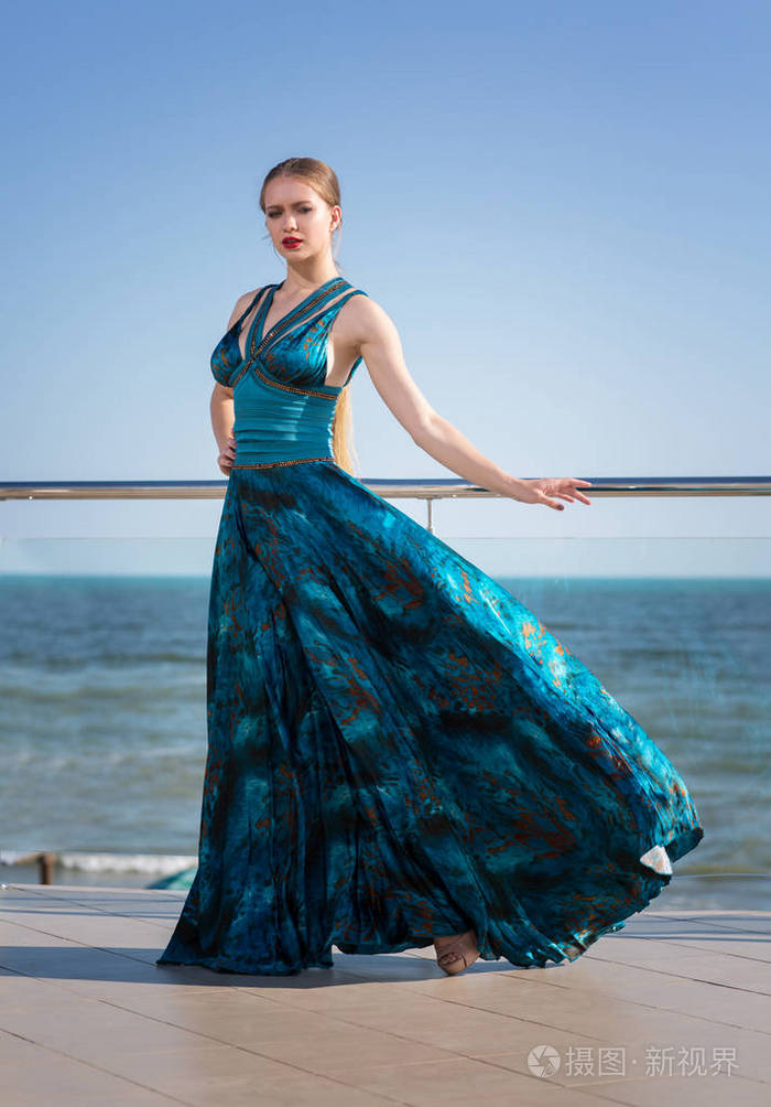 在蓝色天空背景下一个长挥舞着翡翠穿着美丽的女人的全身照观念的女性