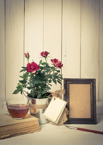 复古相框和旧笔与玫瑰花束在木板上