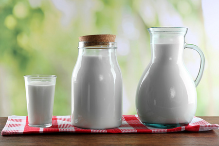 壶 罐 杯牛奶在木桌子上，对自然背景
