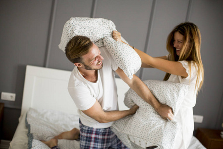 顽皮的年轻夫妇，有枕头战斗在床上