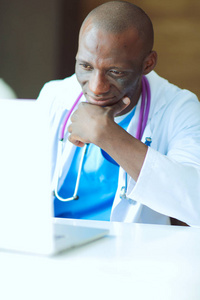 年轻的非洲医生在台笔记本电脑上工作。医生。工作场所