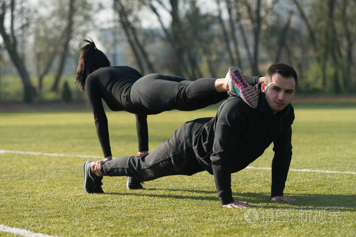有吸引力的情侣在公园里做俯卧撑