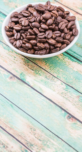 质朴的木制背景的白色碗咖啡豆