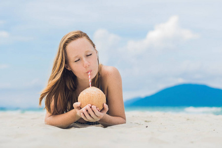 在海滩上喝椰子牛奶的年轻女子
