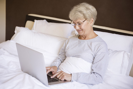 成熟的女人在床上笔记本电脑