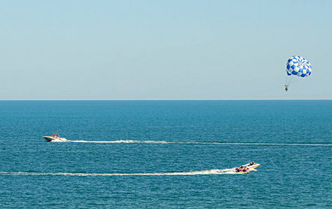 蓝色 parasail 翼拉扯了一艘船在海中，由水上滑翔伞