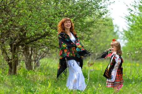 年轻美丽的母亲与她的女儿在花园里散步