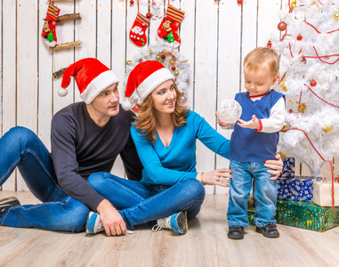 年轻的家庭，在红色的帽子，与附近圣诞树上的小儿子
