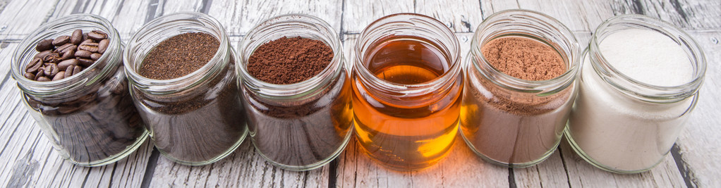 咖啡豆 咖啡粉 奶精 可可粉 蜂蜜制成的茶叶叶片在梅森罐子里超过风化的木制背景