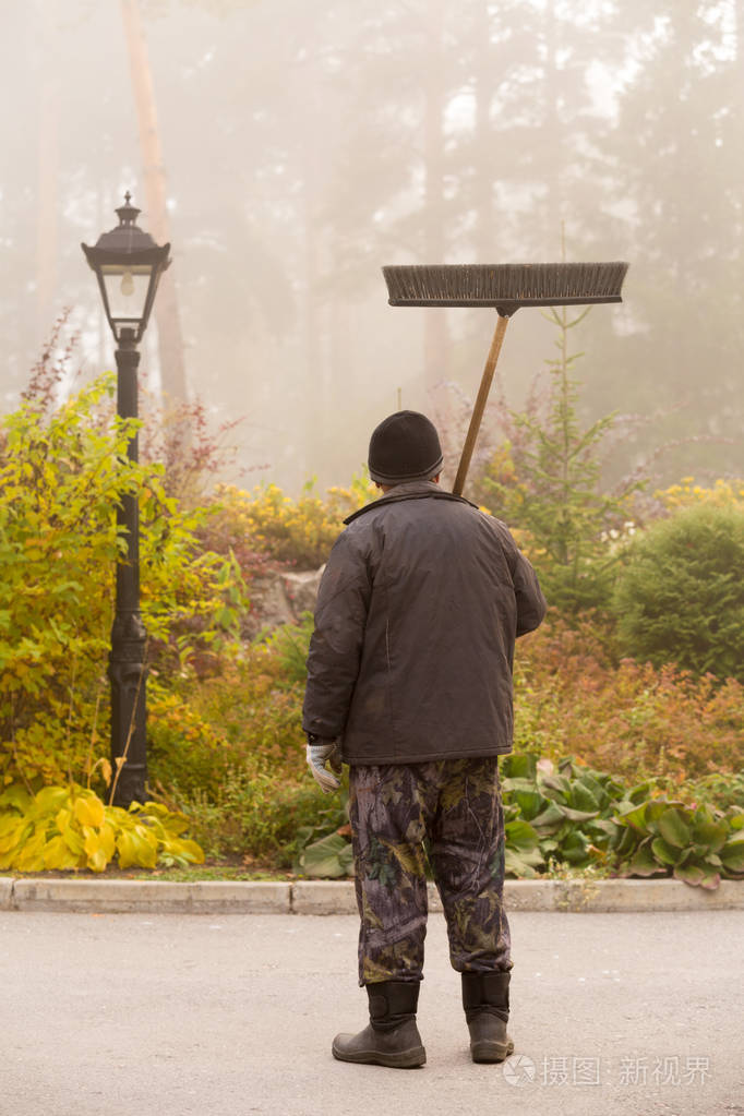 雾的清晨,看门人清理落叶
