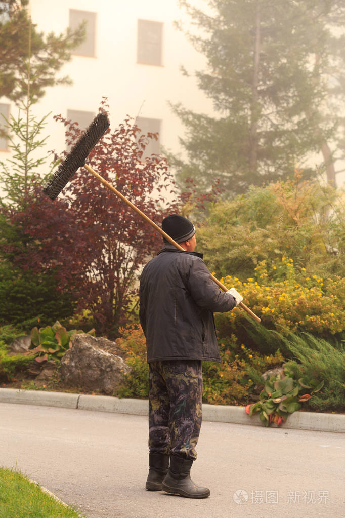 雾的清晨看门人清理落叶