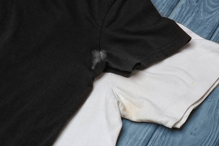 黑色和白色的 tshirts 与汗水和除臭剂在木背景的污渍。卫生概念