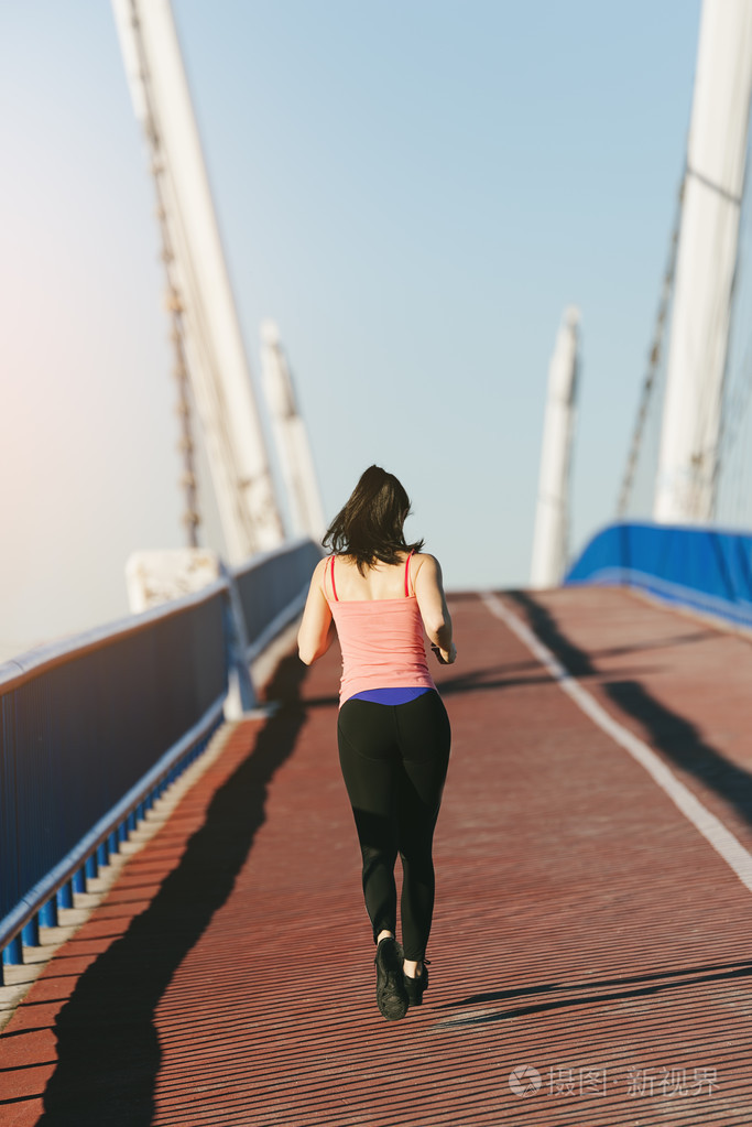 年轻的健身女跑步运动员在城市桥梁上运行照片