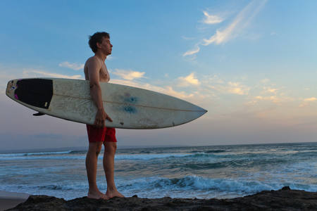 男人的冲浪者，以冲浪板的海岸线。巴厘岛。印度尼西亚