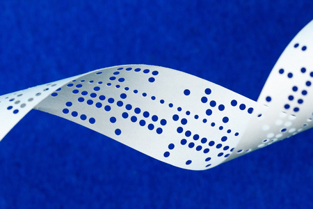 在蓝色背景上的穿孔穿孔纸带的特写照片