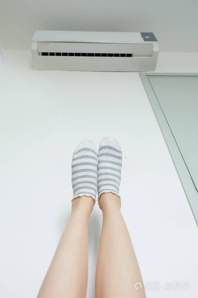 苗条的双腿女人的腿在黄色条纹袜附近门与标签欢迎白墙上在家里