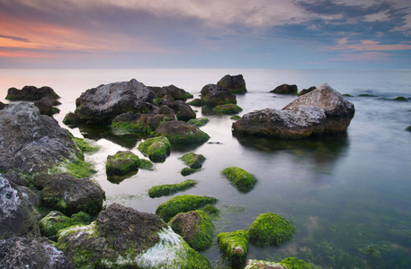 多姿多彩的夏天海景。在日落时的岩石海岸