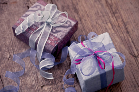 老式圣诞礼品盒, 蓝色和粉红色的丝带在木制背景