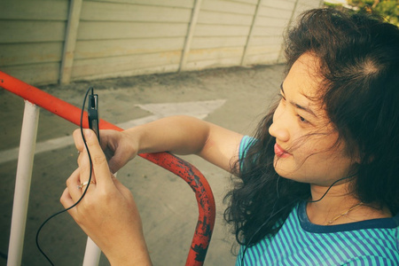 年轻女子在耳机与智能手机上听音乐