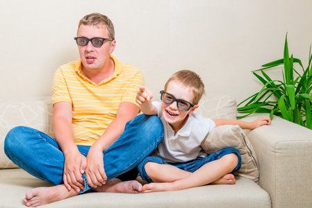 父亲和儿子看有趣的电影在电视上的 3d 眼镜