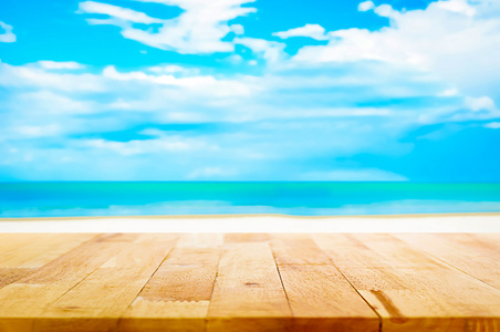 木桌上模糊的白色沙滩和蓝色的天空背景