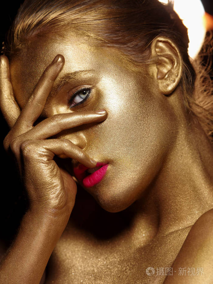 脸被彩色金漆.金黄闪耀的肌肤.工作室黑色背景