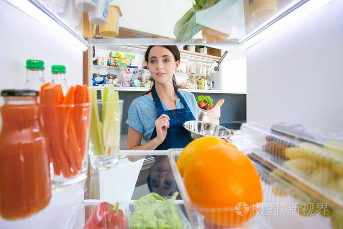 女性站附近打开冰箱充分的健康食品，蔬菜和水果的肖像