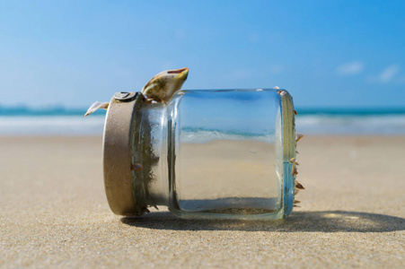 空的玻璃瓶在沙滩与蔚蓝的天空和大海