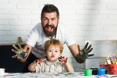快乐家庭艺术 快乐的父亲和儿子让看看手中鲜艳的色彩，画在一起，全家，开朗活泼的绘画老师的艺术。与父母的家庭教育。快乐的童年。在