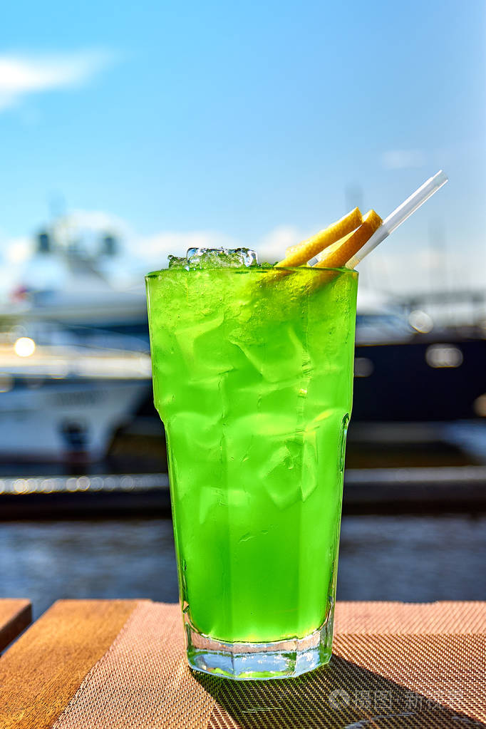 与冰在阳光下闪耀的绿色饮品在岸边休息