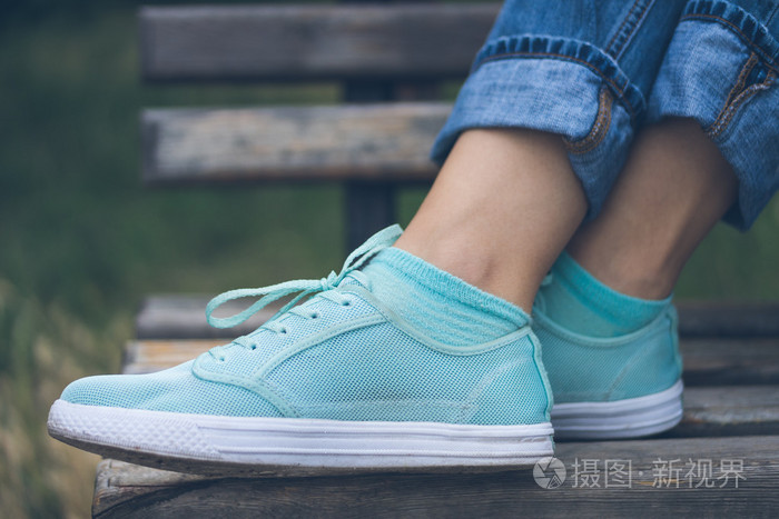 女性的脚在牛仔裤和运动鞋