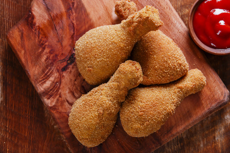 酥脆炸鸡腿在黑板上的面包屑炸鸡腿照片