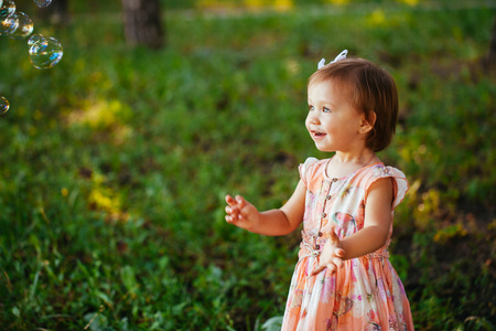 可爱的小女孩玩肥皂泡在公园里