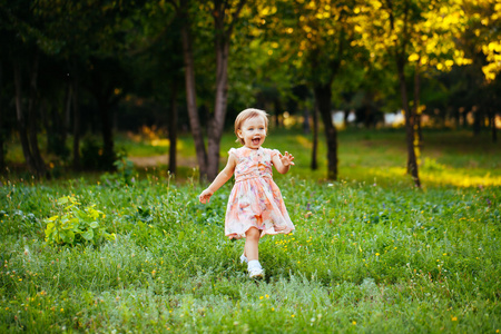 快乐的可爱小女孩在公园草地上跑。快乐