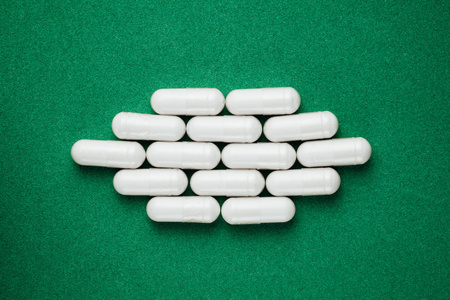 白色胶囊丸对绿色背景照片