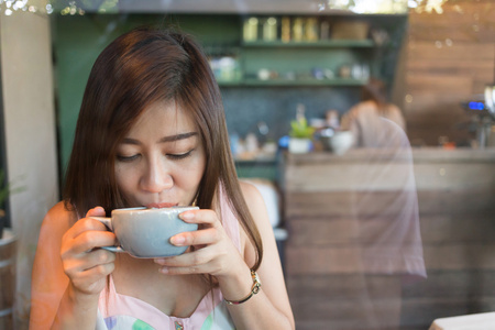 漂亮的女孩在咖啡馆，喝热咖啡或茶模型亚洲妇女