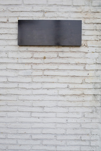 空的黑色符号由白色砖墙上的大理石板
