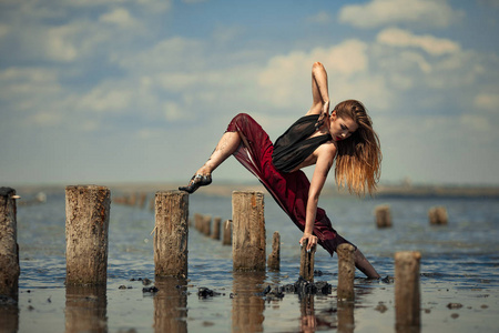 穿红色连衣裙的芭蕾舞演员在海面背景上跳舞在水中