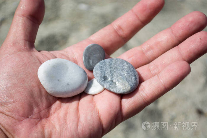 在海滩上的小石头的手照片-正版商用图片0dll0t-摄图新视界