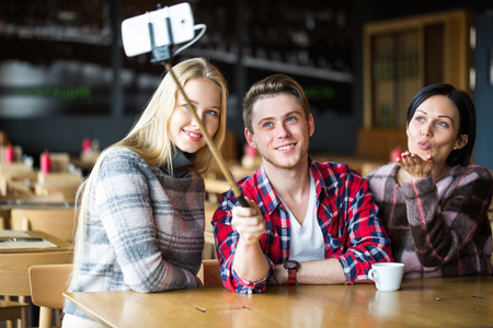 学生在一家咖啡馆使自拍照。男孩和两个女孩在咖啡馆使自拍照