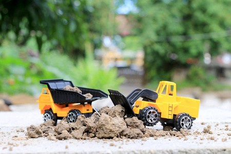 玩具车货车用沙子和土壤在水泥地上与模糊垮掉绿色环境建设设备在工作 建设理念 选择性焦点