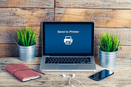发送到打印机的邮件在一台笔记本电脑.计算机在一张小木桌照片