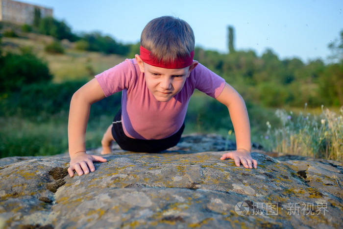 做俯卧撑在一块岩石上的小男孩