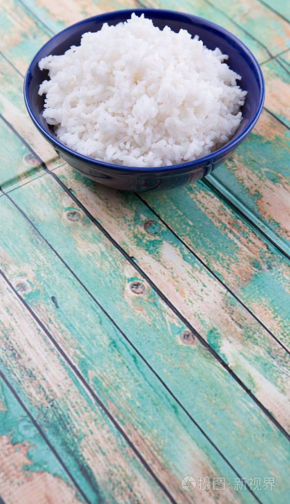 在一个蓝色的碗里蒸米饭在木制的背景