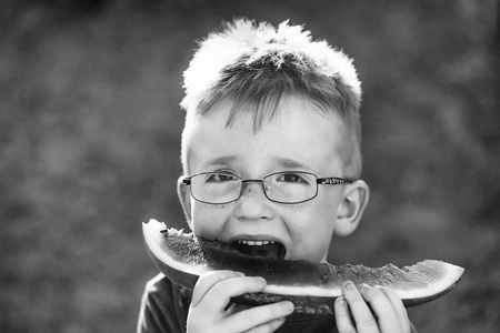 在吃西瓜的眼镜头发的男孩