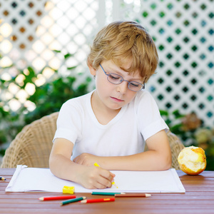 小男孩戴着眼镜制作在家做作业照片