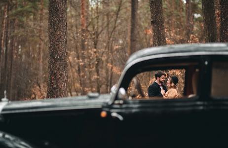 时尚爱婚礼情侣接吻和拥抱在一片松树林附近复古车