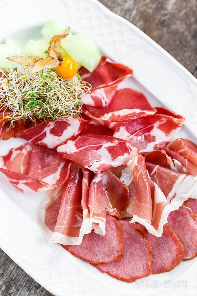 开胃小菜拼盘冷肉板与火腿切片火腿香肠用酸浆和切片的瓜上木制的背景
